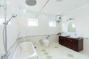 A bathroom with a bathtub, two sinks, a toilet, and a shower.