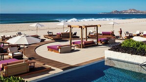 Un espace aménagé au bord de la piscine, avec des chaises longues et des parasols, offrant une vue sur l’océan.