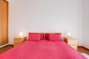 Une chambre à coucher avec un grand lit, deux tables de chevet avec des lampes et une armoire en bois.