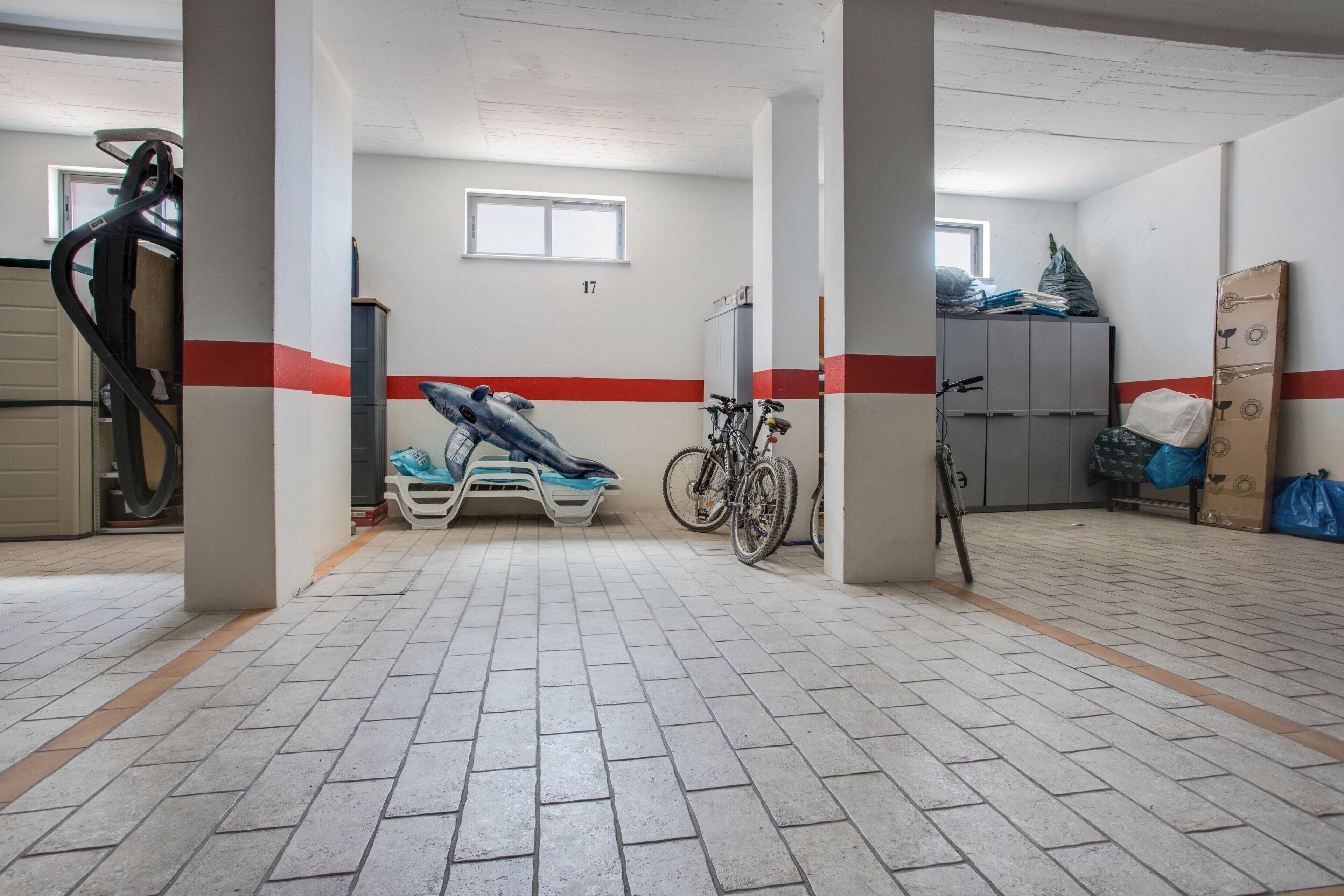 Un pavimento pulito rivestito di piastrelle con una striscia rossa, una rastrelliera per biciclette e una finestra.