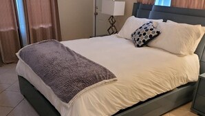 A neatly made bed with a grey headboard, a grey throw blanket, and two patterned pillows. - Hidden gem close to everything!!! (Sarasota)