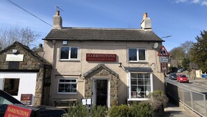 A building with a sign for Harringtons High Class Butchers. - Newly refurbished, modern apartment in Hathersage, with parking (Hathersage)