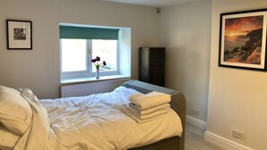 A bedroom with a bed, a window with a view, a dresser, and a painting on the wall. - Newly refurbished, modern apartment in Hathersage, with parking (Hathersage)