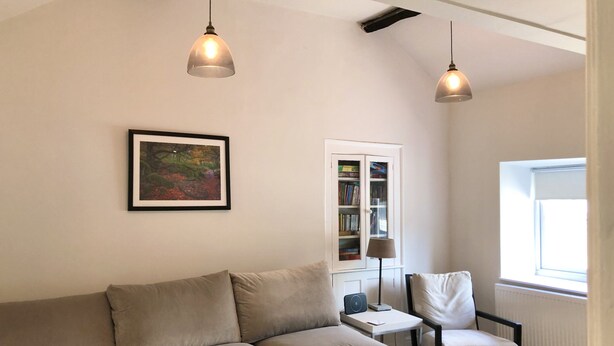A living room with a sofa, a chair, a bookshelf, and two pendant lights. - Newly refurbished, modern apartment in Hathersage, with parking (Hathersage)