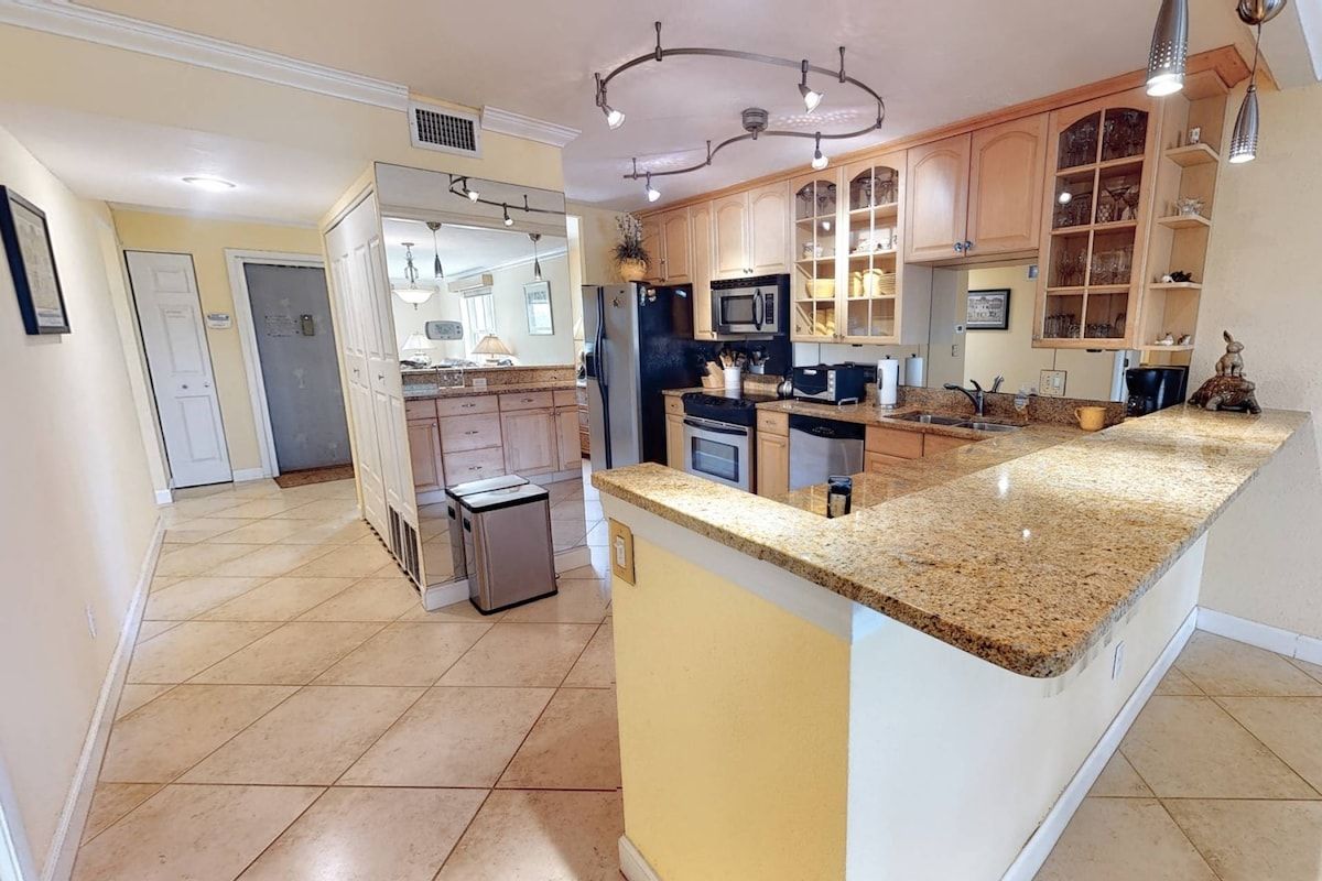 A spacious kitchen with granite countertops, stainless steel appliances, and wooden cabinets.