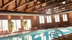 Une piscine intérieure avec des poutres en bois, de grandes fenêtres laissant entrer la lumière du soleil et des chaises longues.