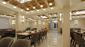 Un comedor moderno con varias mesas y sillas, paneles de techo de madera e iluminación empotrada.
