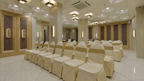 Un salón amplio y bien iluminado con filas de sillas cubiertas con telas color beige, dispuesto para un evento.
