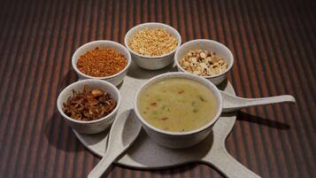 Una mesa con un tazón de sopa y cinco recipientes pequeños con distintos condimentos.