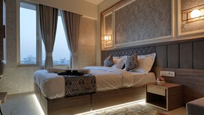 Un dormitorio moderno con una cama grande, mesitas de noche y vistas de la ciudad a través de amplios ventanales.