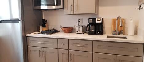 Una cocina moderna con electrodomésticos de acero inoxidable, un microondas, un tostador y una cafetera.