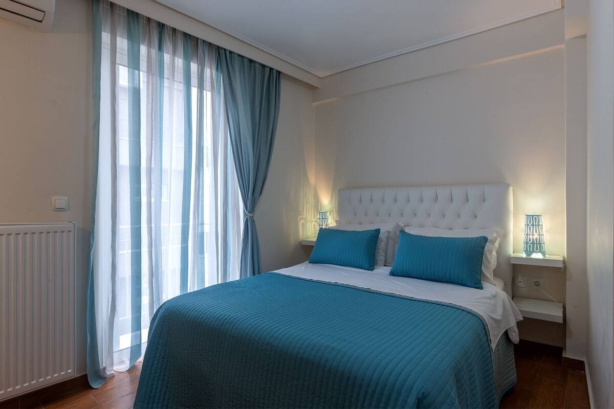 Quarto com cama, cortinas, radiador e abajures.