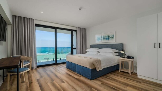 A modern bedroom with a large bed, a desk, and a view of the ocean. - Paxton Luxury Apartments (Gqeberha (Port Elizabeth))