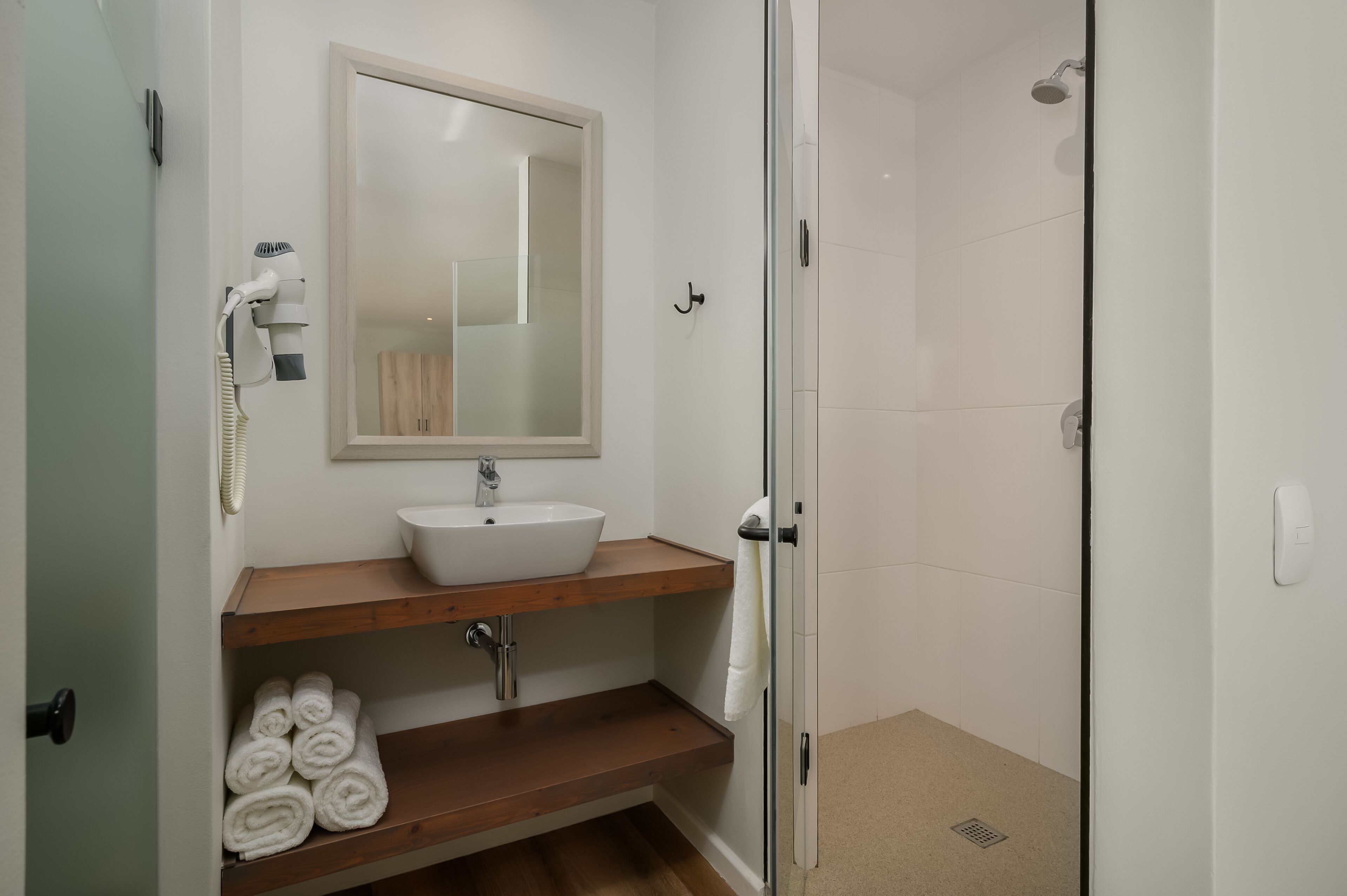 A bathroom with a white sink, a mirror, and a glass shower enclosure.