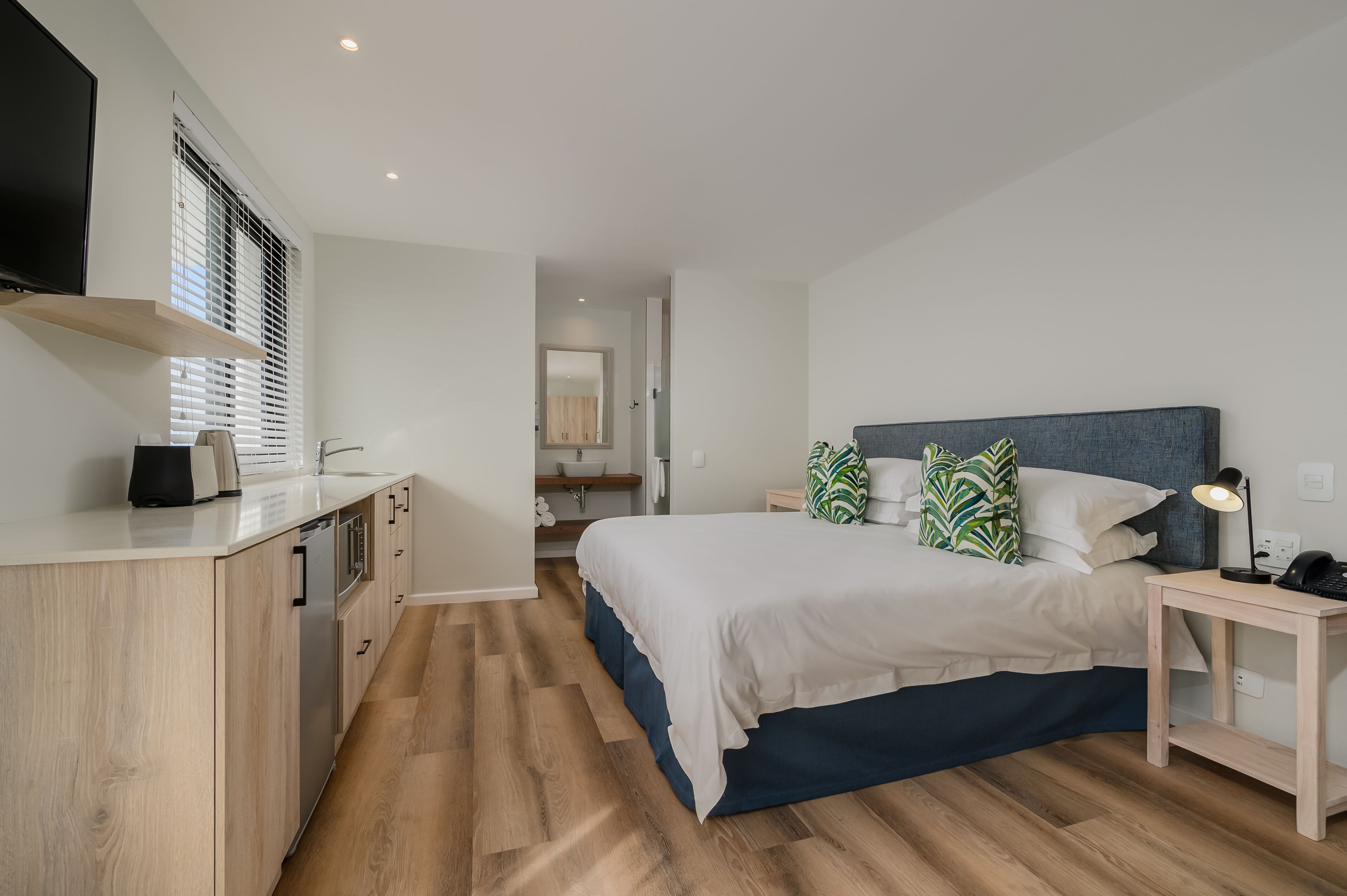 Une chambre à coucher moderne avec un lit, une table de chevet et un petit espace bureau.