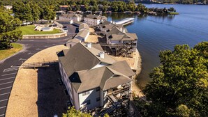 A lakeside hotel with multiple buildings, a parking area, and a boat dock. - Evergreen 209 - Lower Level 3 Bdrm Lakefront Condo (Sunrise Beach)