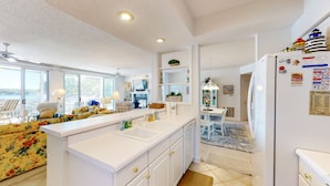 A bright kitchen with white cabinets, a central island, and a view of the outdoors. - Evergreen 209 - Lower Level 3 Bdrm Lakefront Condo (Sunrise Beach)