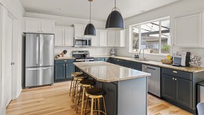 Una cocina moderna con electrodomésticos de acero inoxidable, una isla grande, taburetes de bar y vistas al exterior.