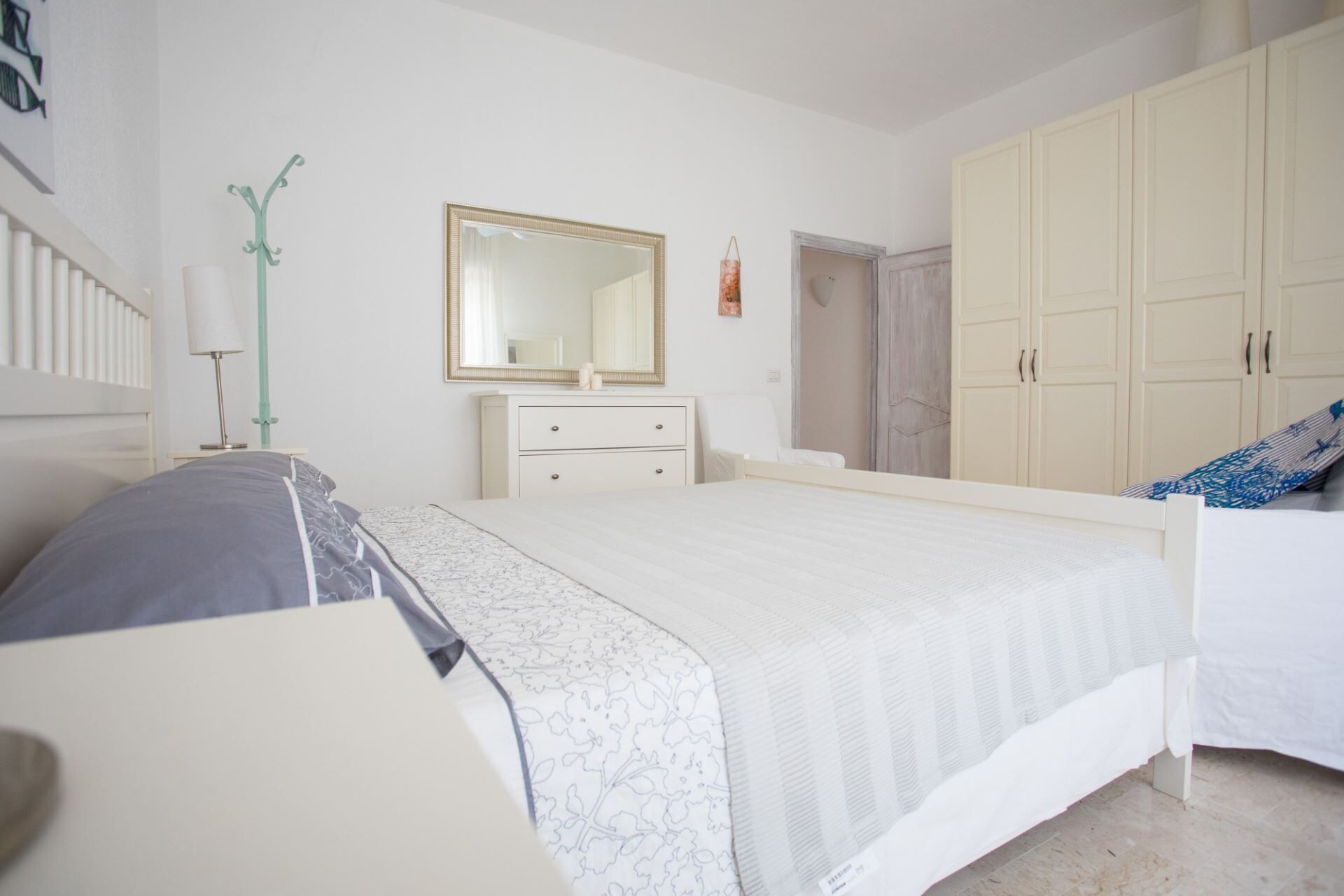 A bedroom with a bed, a dresser, a mirror, and a wardrobe.