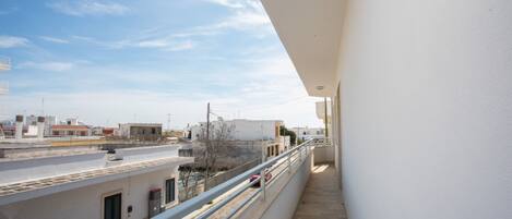 A balcony with a clear view of the surrounding buildings and a street.