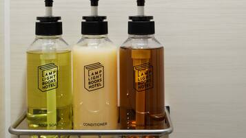 Three bottles of body soap, conditioner, and shampoo on a metal rack.