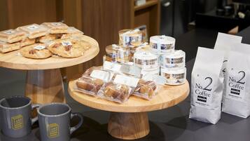 Una exhibición de pasteles, café y tazas sobre un mostrador de madera en un café.