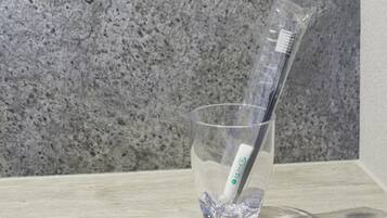 Un vaso transparente con un cepillo de dientes y pasta dental.