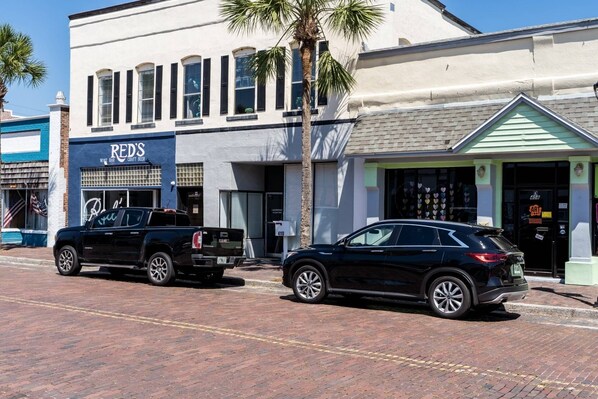 A street view with a building labeled 'RED'S' and a parked black SUV.