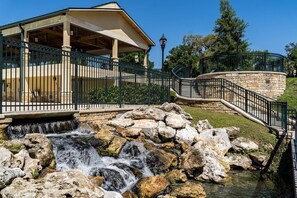 Relax in a serene outdoor setting with a soothing waterfall and shaded pavilion.