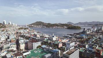 A densely packed urban area with a large body of water in the background, surrounded by hills.