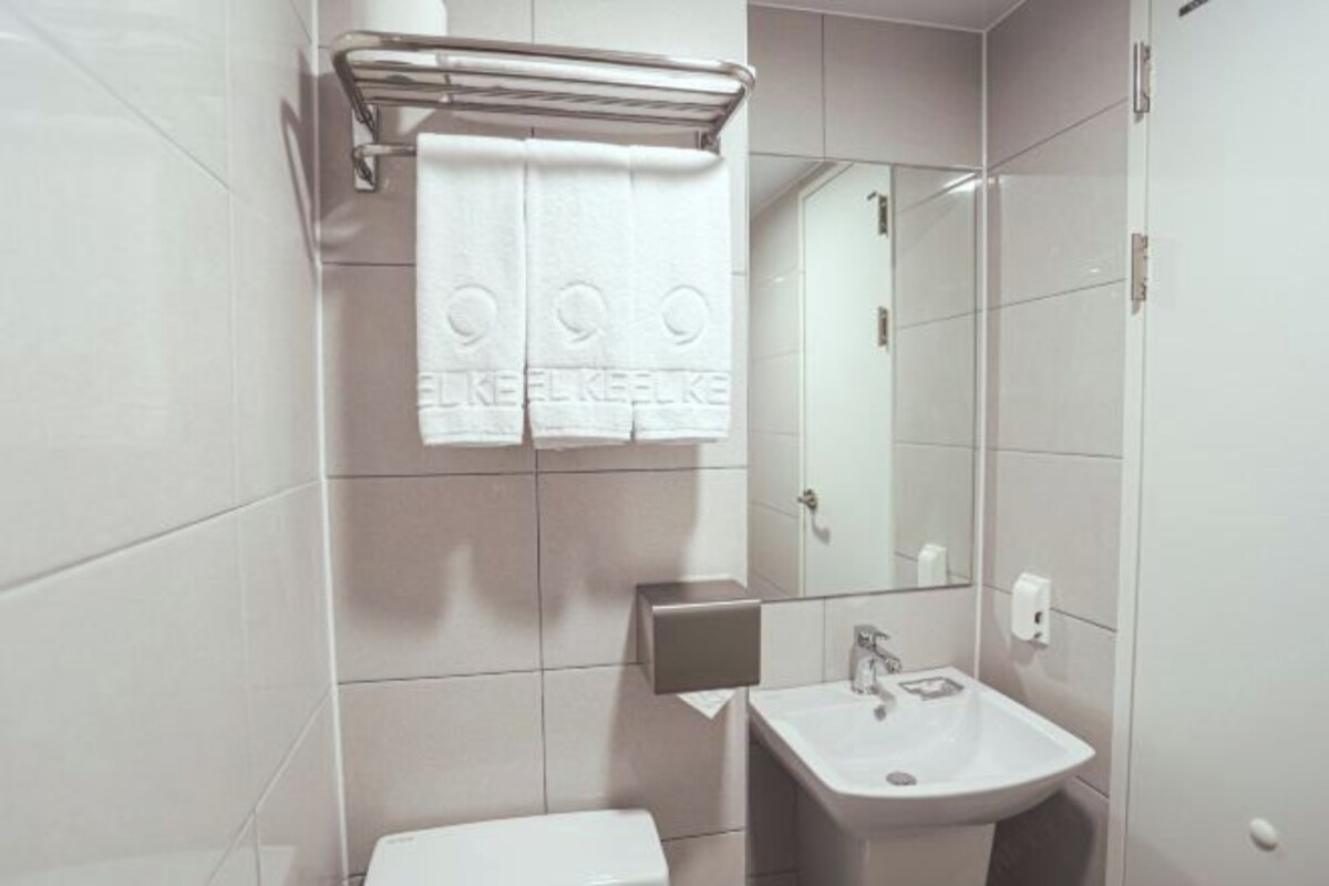 A modern bathroom with a white sink, a mirror, and a towel rack.