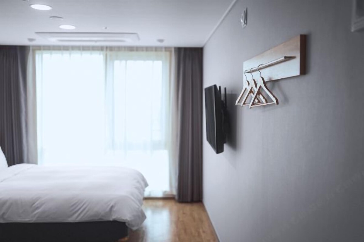Una habitación de hotel moderna con una cama, un televisor de pantalla plana en la pared y una ventana con cortinas.
