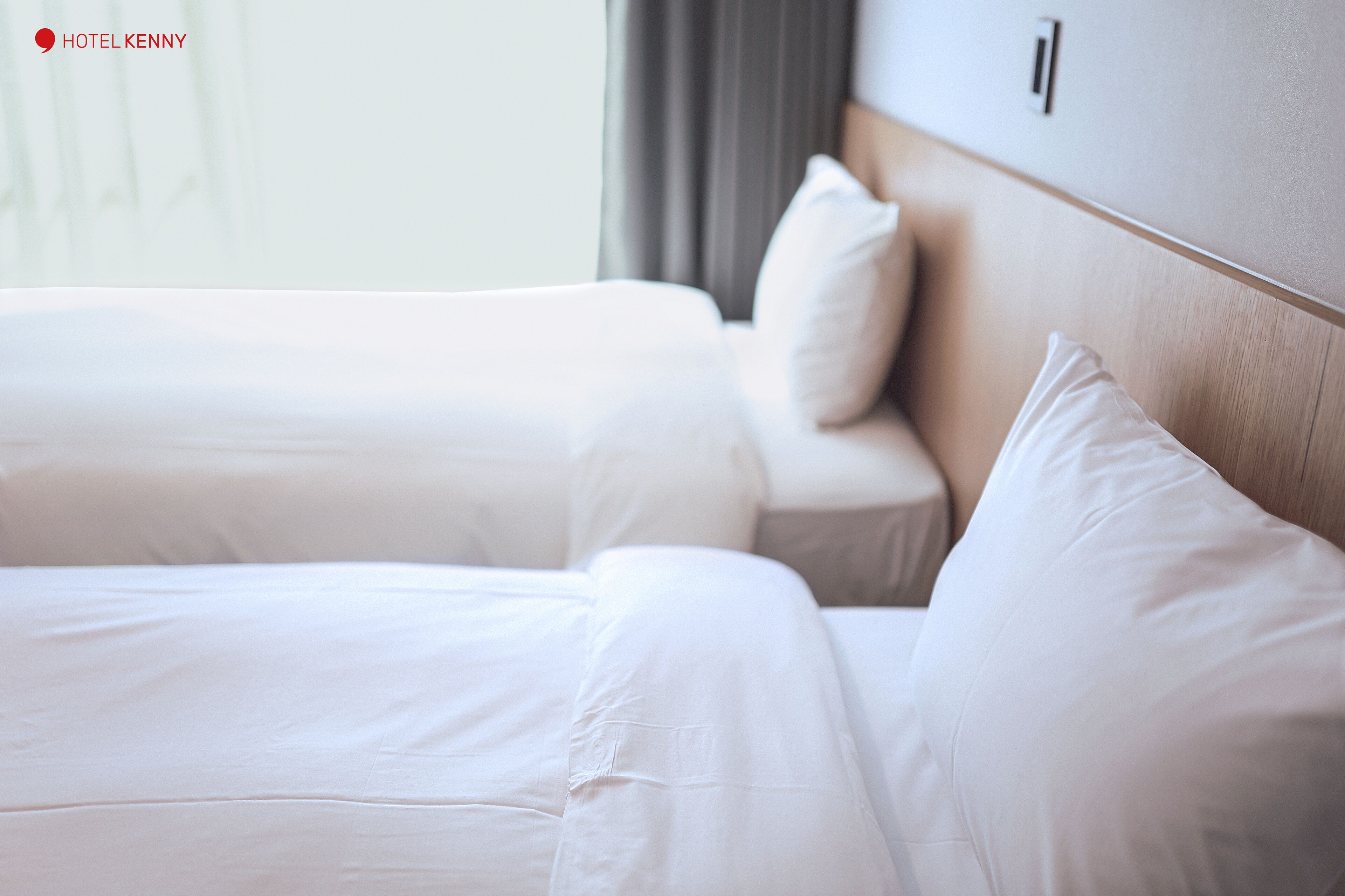 A hotel room with two beds, each with white bedding and pillows.