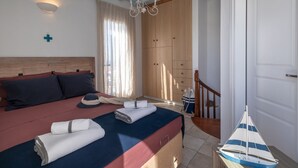 Un dormitorio con cama, cabecera de madera, candelabro, armario y un pequeño modelo de velero.