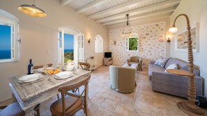 A spacious living area with a dining table set for four, a sofa, and a television.
