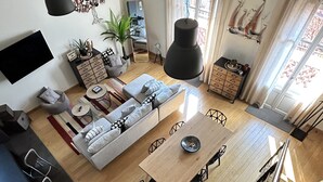 A modern living space with a dining area, sofa, and a staircase.