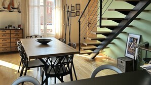 A dining area with a table and chairs, a staircase, and a view of the outside.