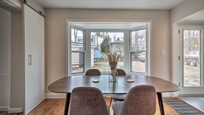 A dining area with a large table, four chairs, and a vase with flowers. - Home w/ Office + Yard: 25 Mi to Downtown Chicago! (Glen Ellyn)