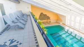 Area piscina con lettini e una parete decorativa.