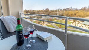 Ein Balkon mit Tisch, einer Weinflasche, zwei Weingläsern und einem Buch.