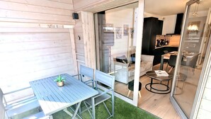 A small patio area with a table and chairs, a small round table, and a glass door leading to a kitchen area. - Flat for 4, central Les Gets, WiFi, parking (Les Gets)