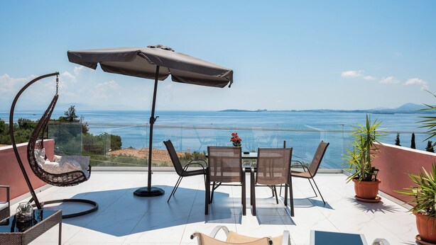 A terrace with a table, chairs, an umbrella, and potted plants. - Ionian Sea View Apartments at Barbati by Konnect (Corfu)