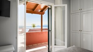 A bedroom with a view of a balcony, a bed, and a wardrobe. - Ionian Sea View Apartments at Barbati by Konnect (Corfu)