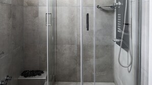 A modern shower enclosure with a glass door, a handheld showerhead, and a handheld shower attachment. - Ionian Sea View Apartments at Barbati by Konnect (Corfu)