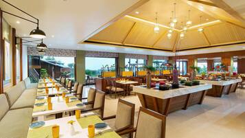 A spacious dining area with multiple tables and chairs, a long bench, and a central island with a marble countertop.