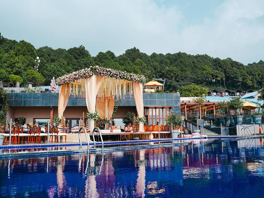 Un hotel con piscina, zona de estar al aire libre y un espacio cubierto decorado con flores.