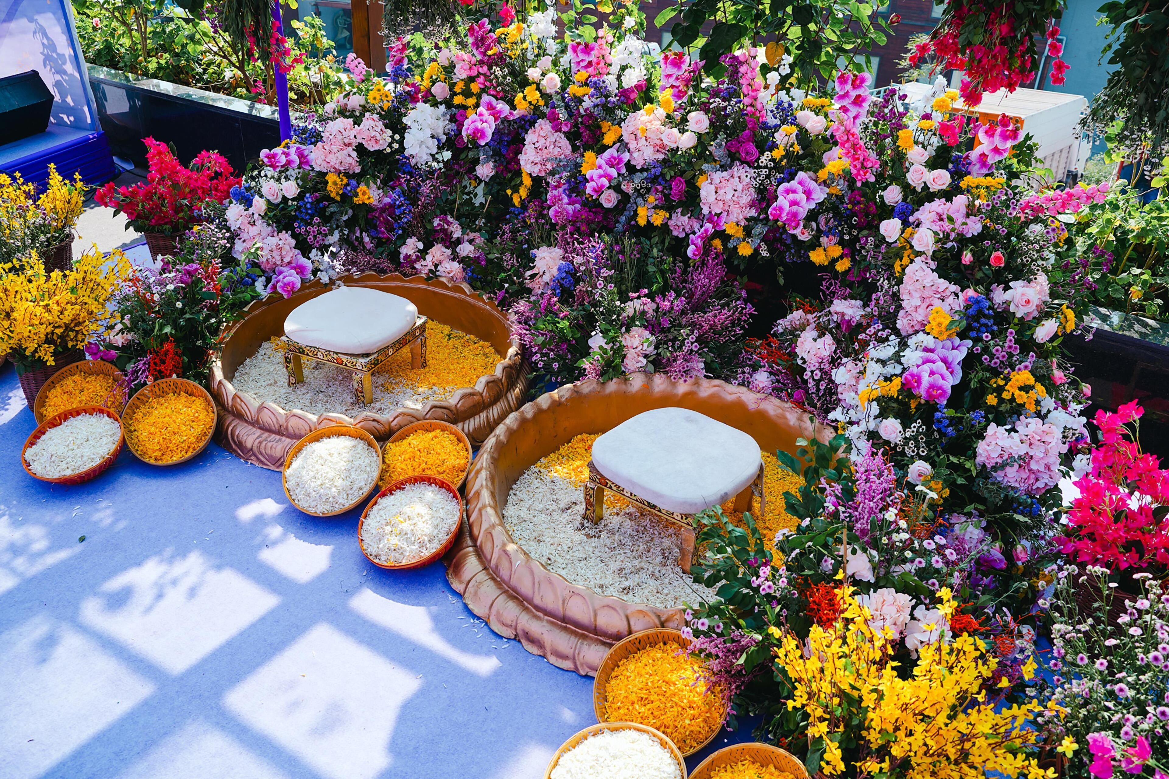 A colorful outdoor display of flowers and bowls of rice.