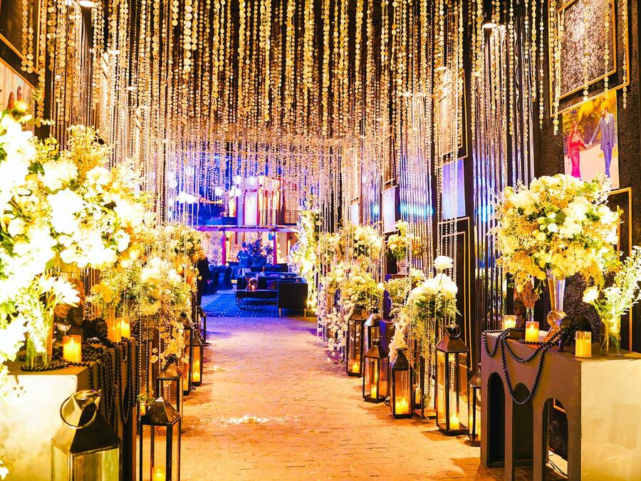 A decorated aisle with floral arrangements and lanterns, leading to a stage area.