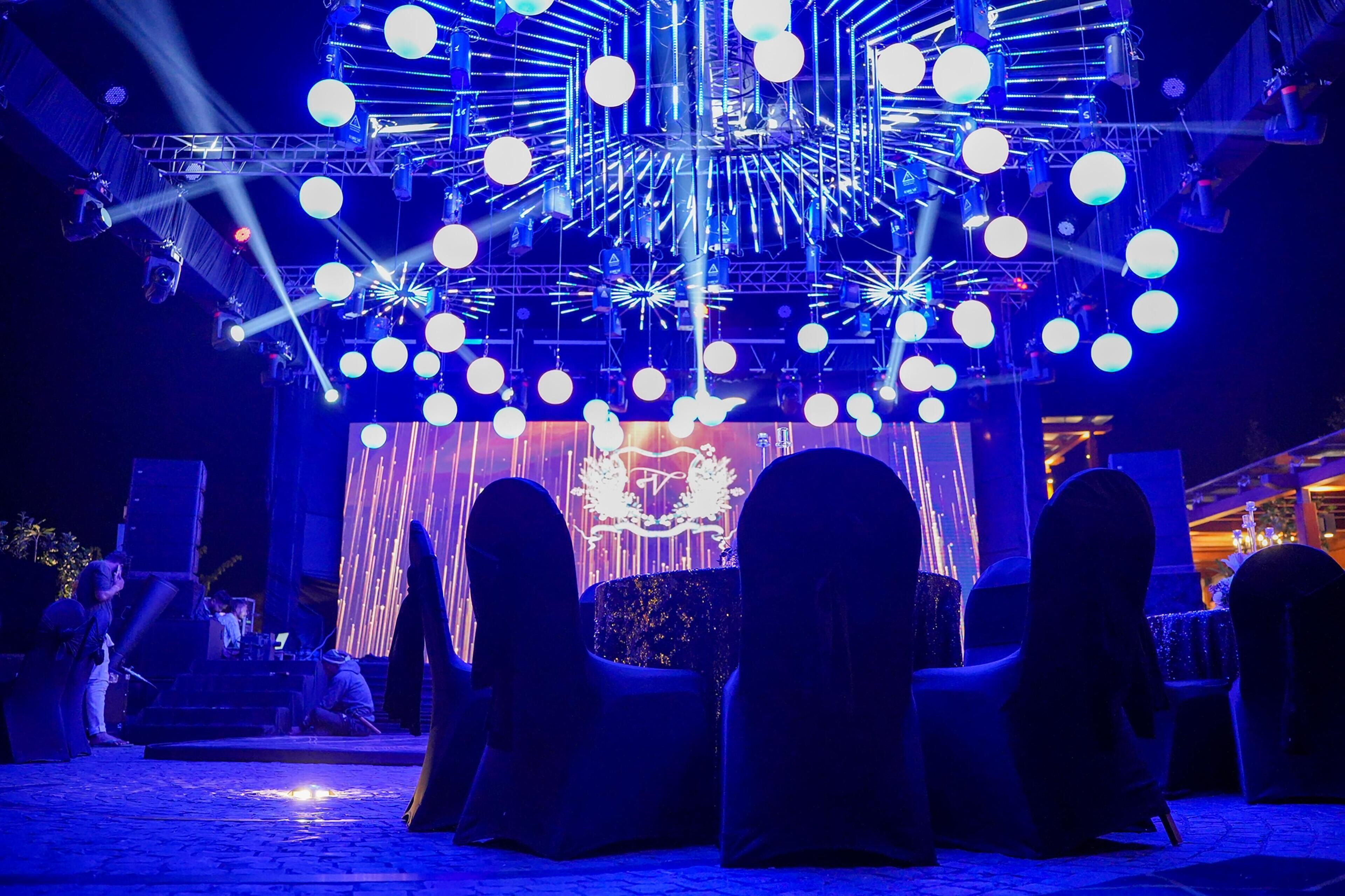A stage with a geometric light installation and a backdrop with a crest.