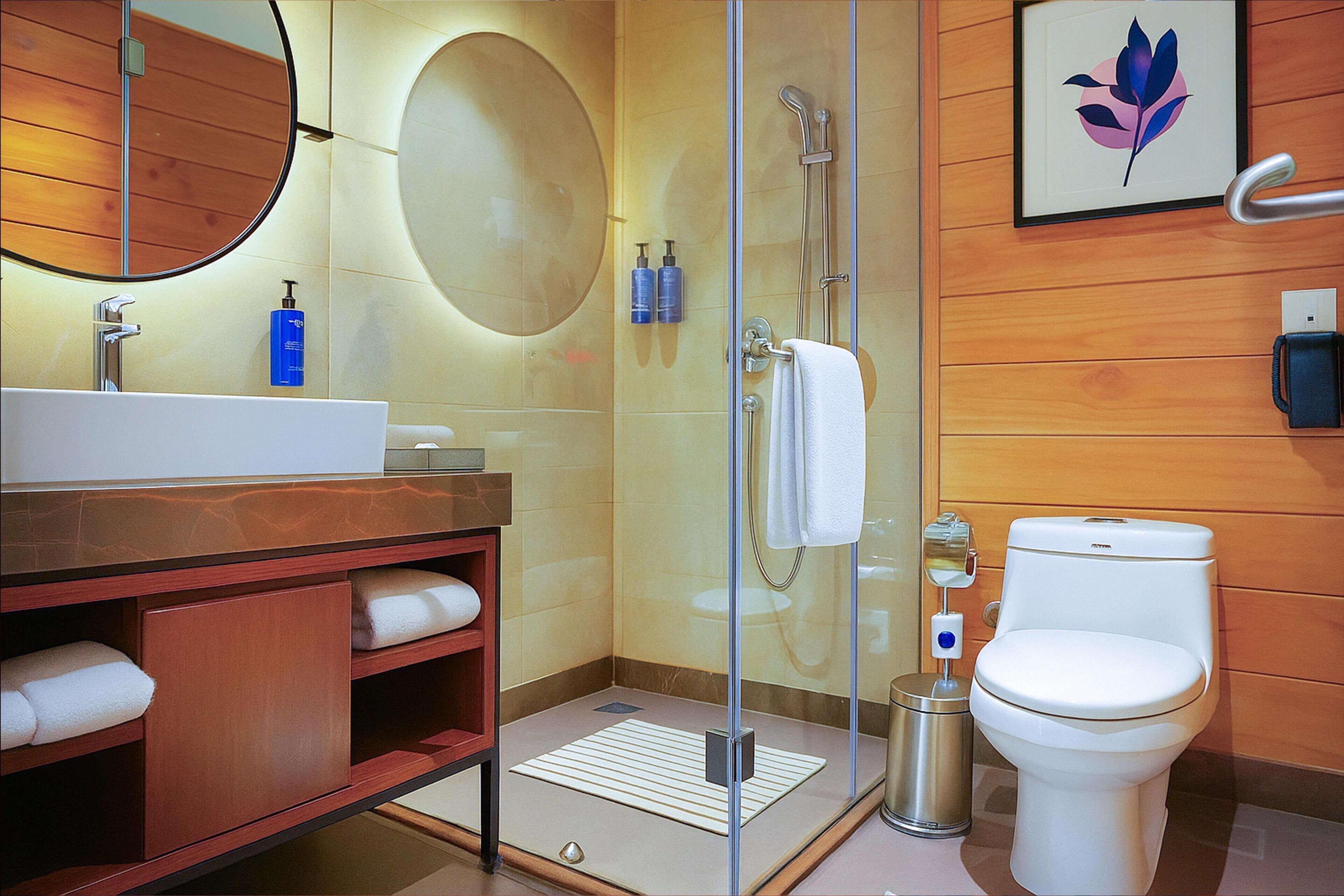 A modern bathroom with a glass-enclosed shower, a white toilet, and a wooden vanity with a sink and towel storage.